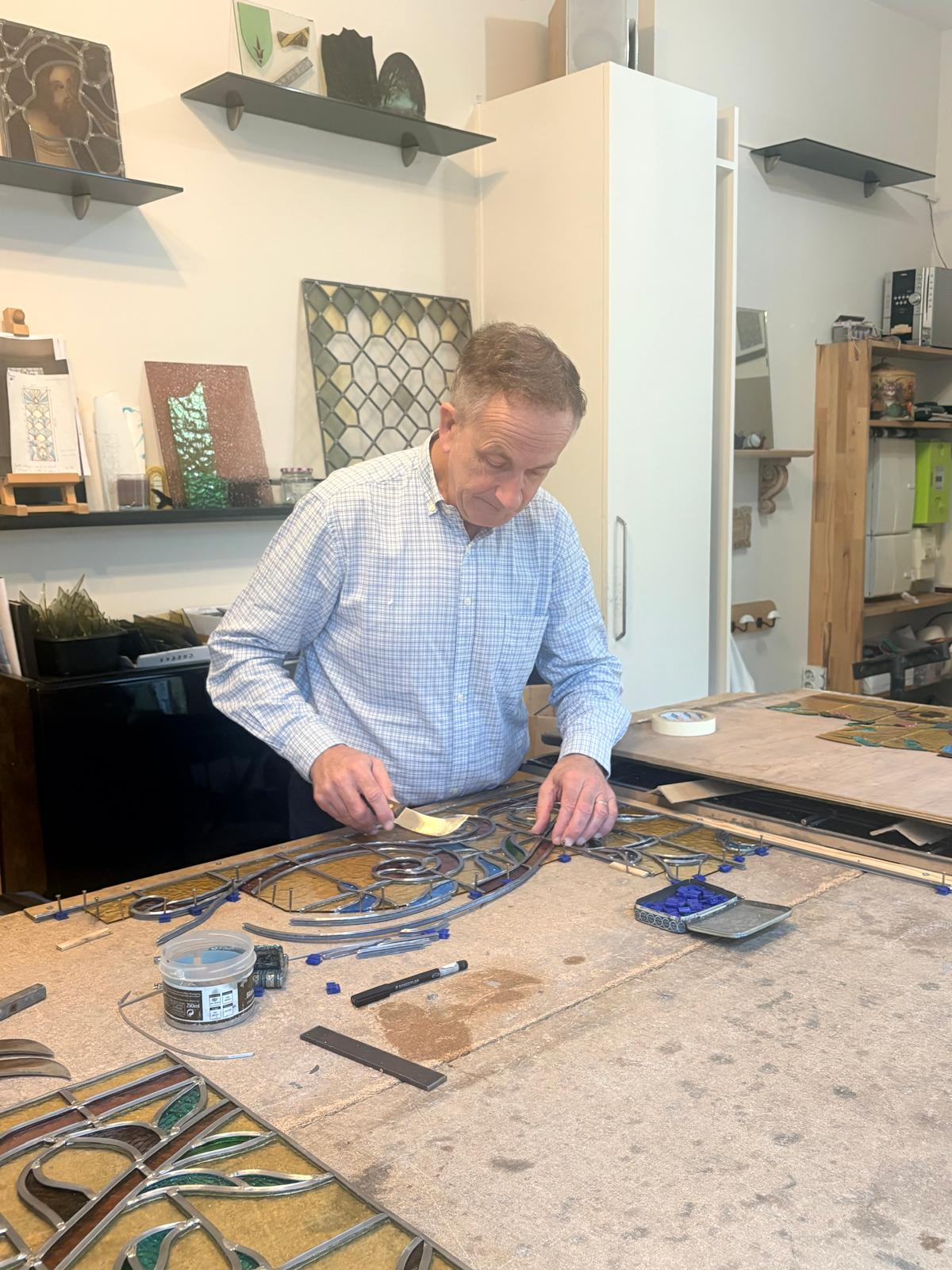 Pierre Bertin au travail sur un vitrail posé sur l'établi de son atelier à Lille